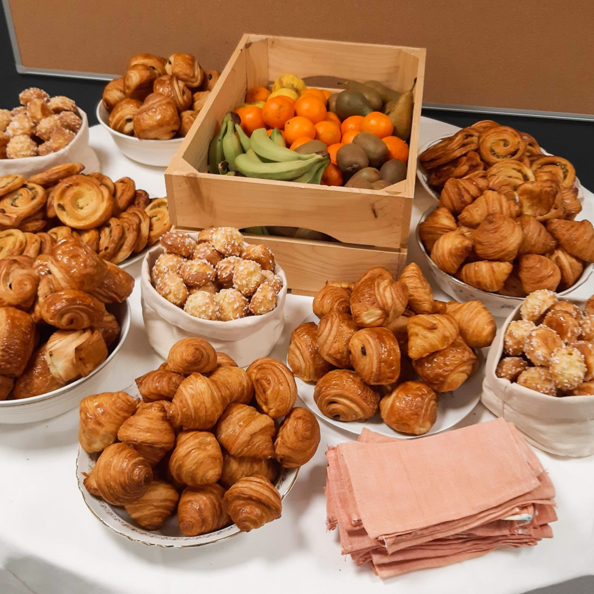 Assortiment de viennoiseries et fruits pour un petit-déjeuner au bureau